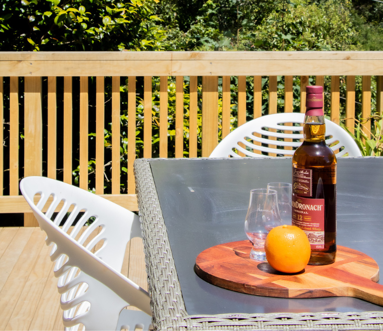White outdoor chairs and glass table on newly built wooden deck