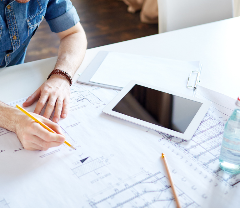 House plans with an architect reviewing them and an ipad. Woodfort Construction House and Land packages.